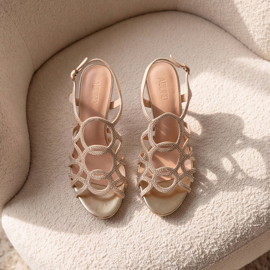 A pair of metallic gold strappy high-heeled sandals with rhinestone embellishments