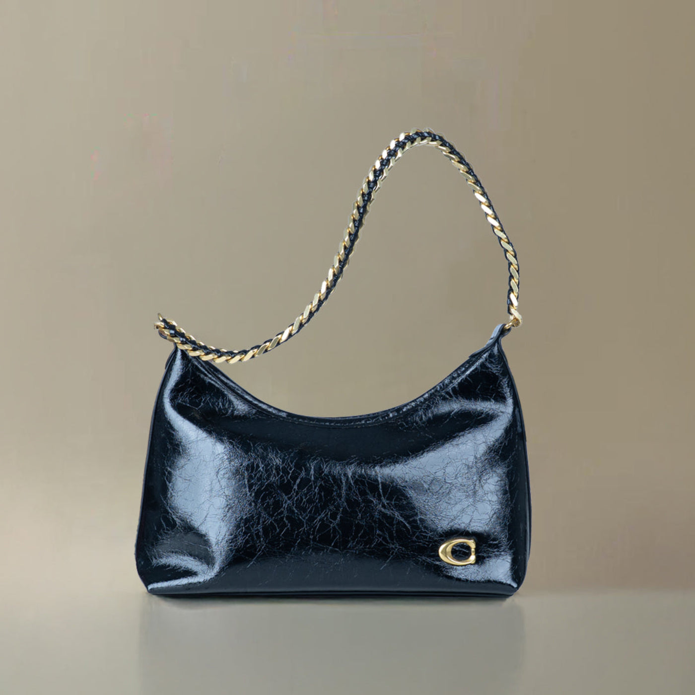 Black handbag with a chain strap on a beige background